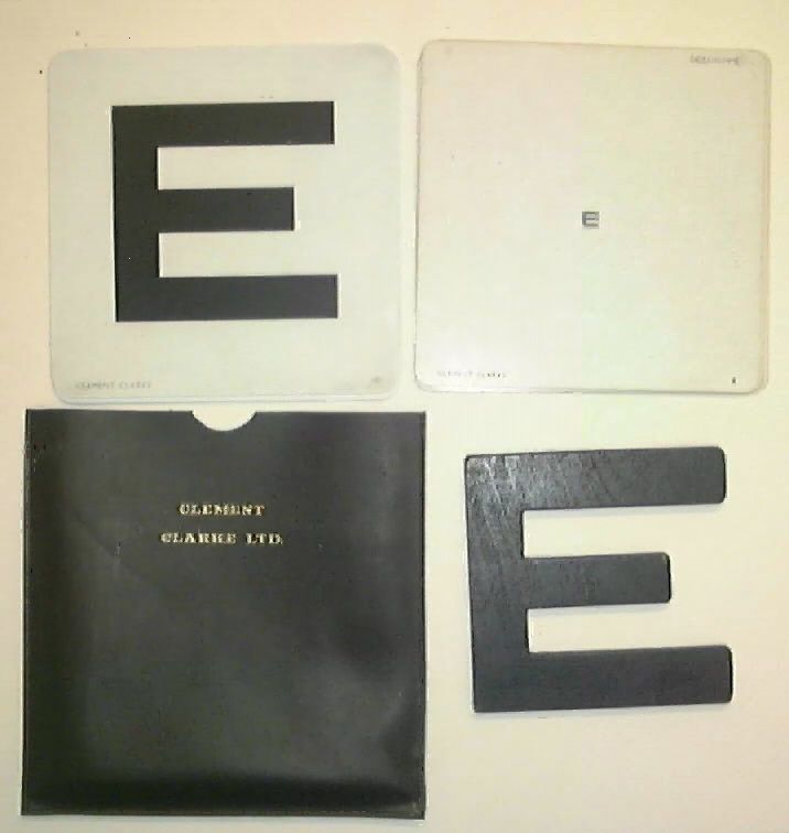 Four cards laid out on a table. Three are white with the letter E written in varying sizes. One is black with the name Clement Clarice LTD engraved.