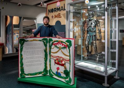 Artist Andy Singleton with one of his paper art installations in front of medical displays