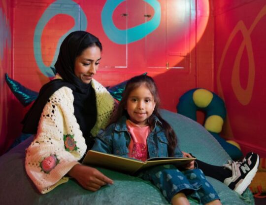 A child reading with her mother on a bean bag.